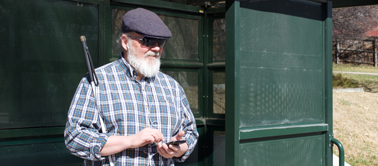 A man listens to NFB-NEWSLINE at a bus stop.